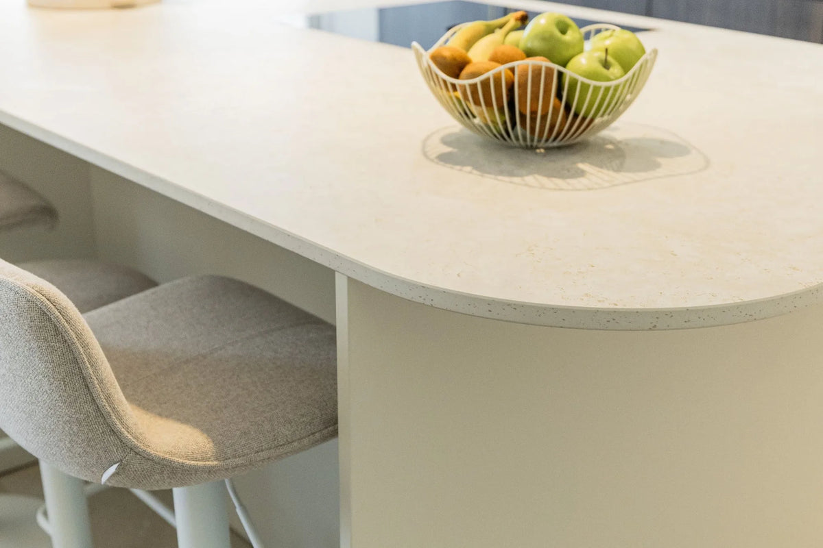 Chant arrondi d’un îlot en Dekton Sabbia, plan beige légèrement moucheté